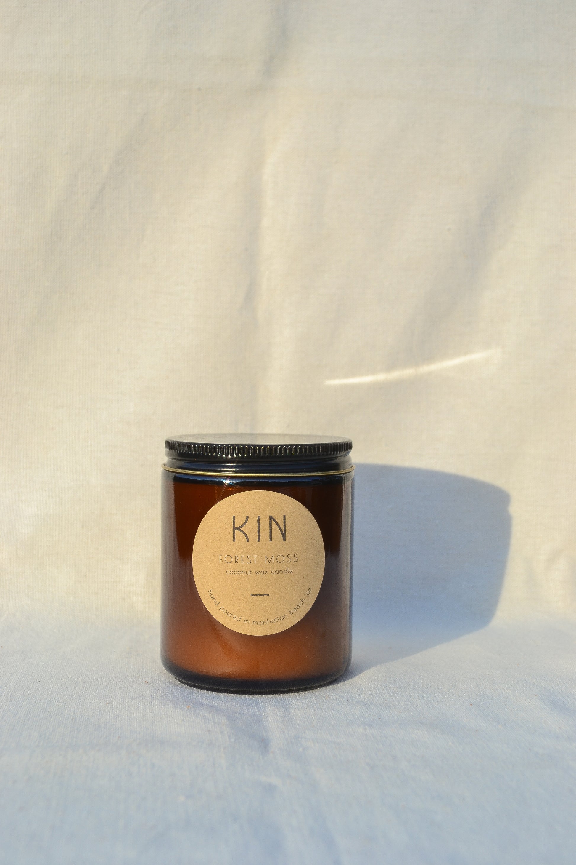 Forest Moss Candle by Kin Candle Co. Grounded and vivacious. Like wandering an earthy trail under the canopy of ancient Big Sur redwoods. This scent is a breath of fresh air, reconnecting the mind with the natural world with scent notes of Amber, Redwoods, and Citrus.
