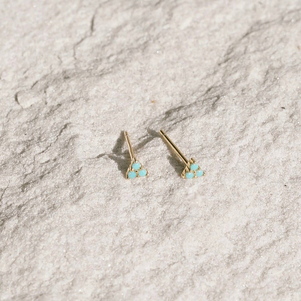 A tiny delicate triangular stud earring with triple prong set turquoise stones. Handmade in the Santa Cruz Mountains.