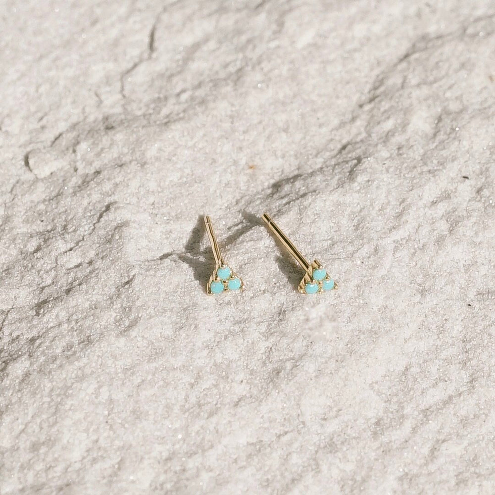 A tiny delicate triangular stud earring with triple prong set turquoise stones. Handmade in the Santa Cruz Mountains.